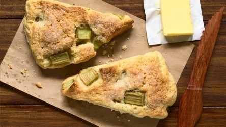 Zwei Rhabarber-Scones in der Draufsicht. Daneben ein Stück Butter.