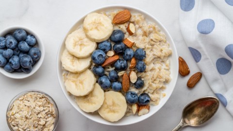 Eine Schüssel Soja-Porridge mit Bananen, Blaubeeren und Mandeln in der Draufsicht.