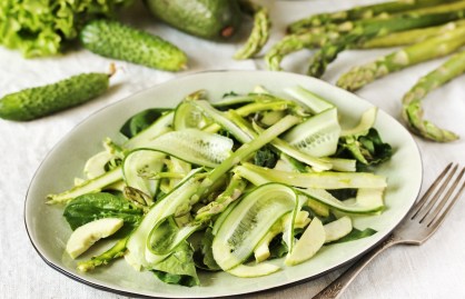 Ein Teller Spargel-Gurken-Salat, drumherum kleine Gurken und grüner Spargel.