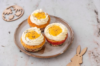 Drei Spiegelei-Cupcakes auf einem Teller. Daneben liegt ein Holz-Osterhase.