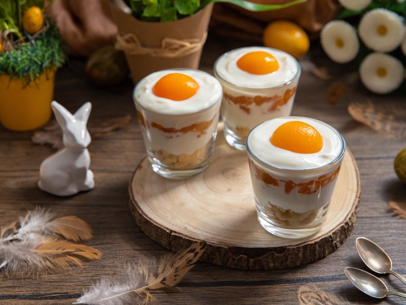 Drei Gläser mit Spiegelei-Dessert auf einem Tisch, Osterdeko daneben