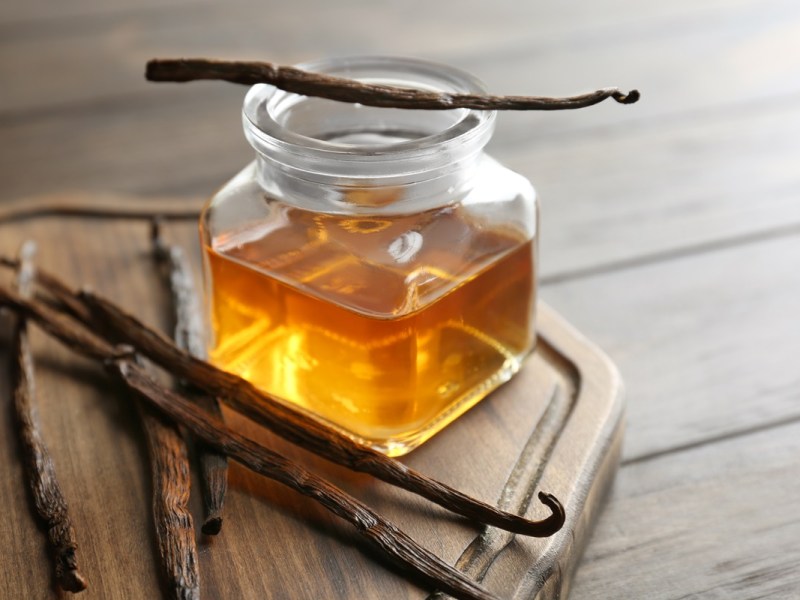 Glas mit Vanilleextrakt und Vanilleschoten