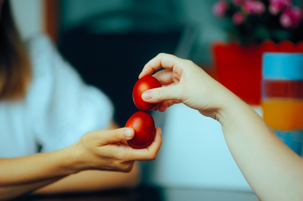 Warum gibt es Ostereier? Zwei Menschen beim Ostereiertitschen.