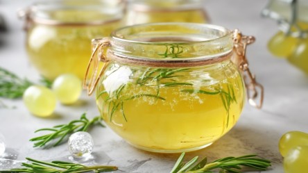 Mehrere Gläser weißes Traubengelee mit Rosmarin.