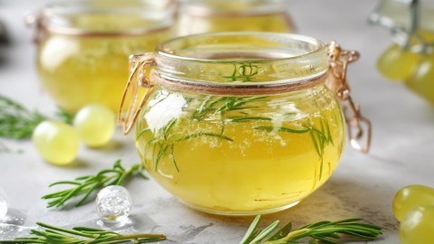 Mehrere Gläser weißes Traubengelee mit Rosmarin.
