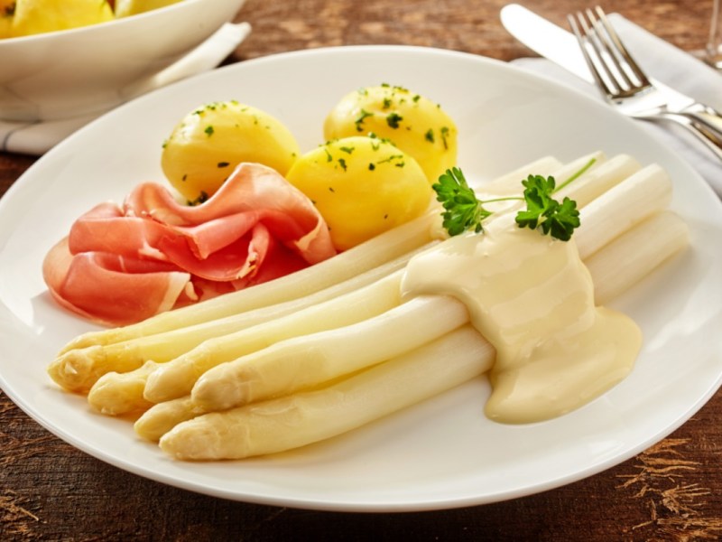 Wie viel Spargel pro Person: eine Portion Spargel mit Sauce hollandaise und Kartoffeln auf einem Teller.