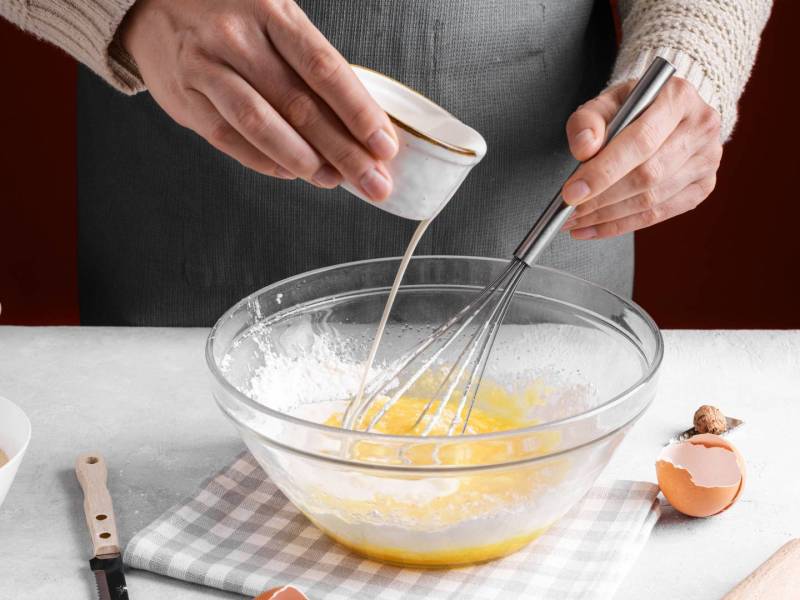 Backen ohne Butter: ein Mensch gießt Milch in eine Schüssel mit Eiern.