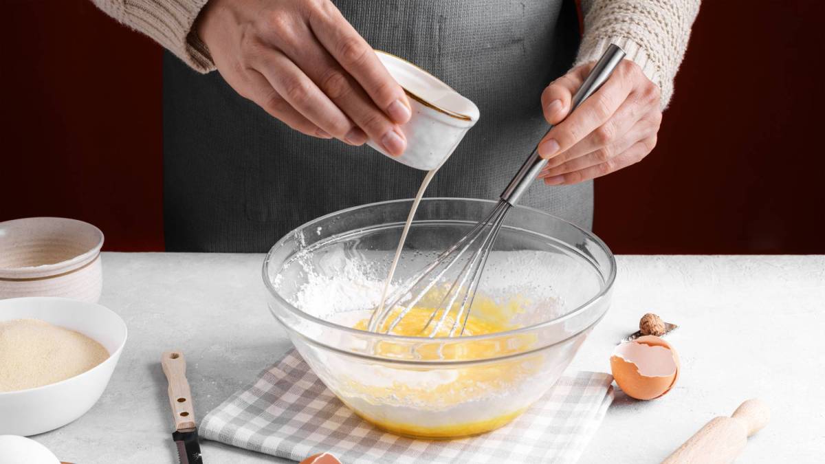 Backen ohne Butter: ein Mensch gießt Milch in eine Schüssel mit Eiern.