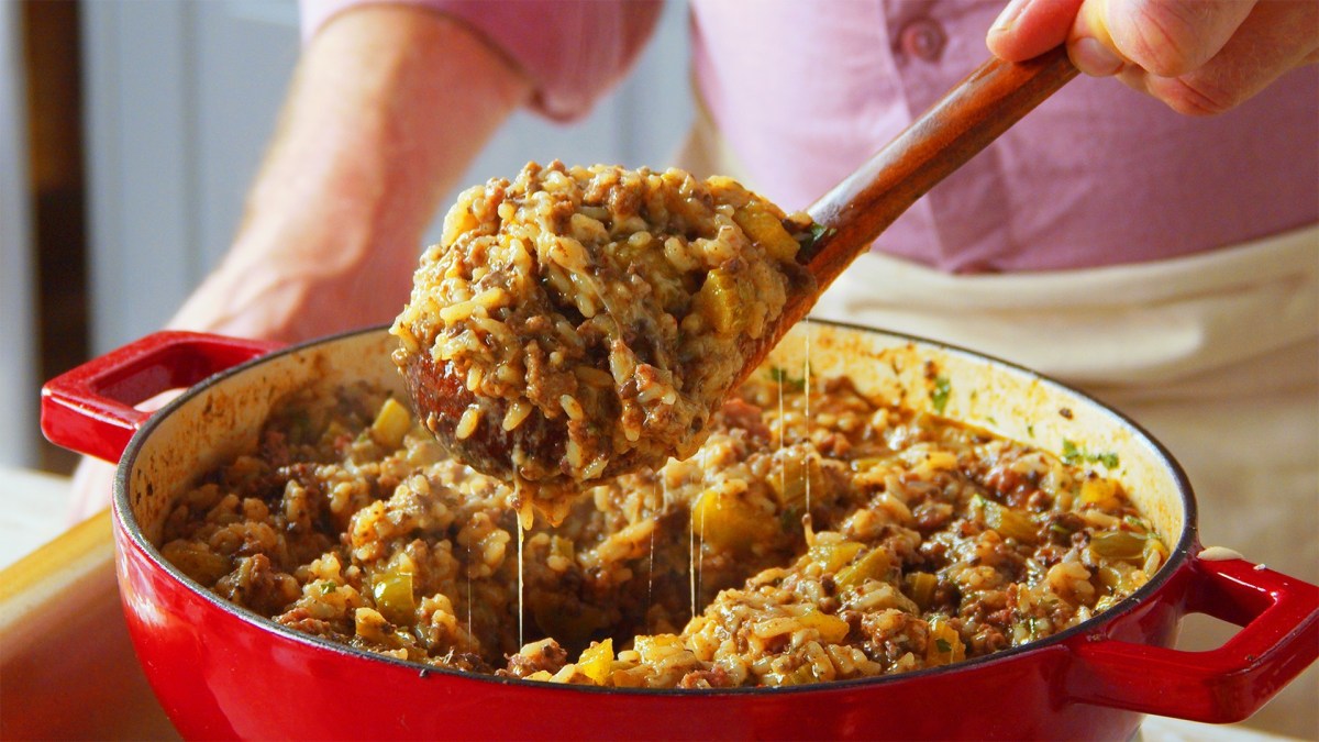 Eine Pfanne Cajun Style Dirty Reis, aus der mit einem Löffel eine Portion entnommen wird.