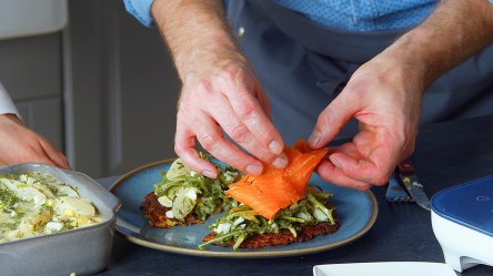 Berner Rösti mit Spargelsalat, auf die eine Scheibe Räucherlachs gelegt wird.