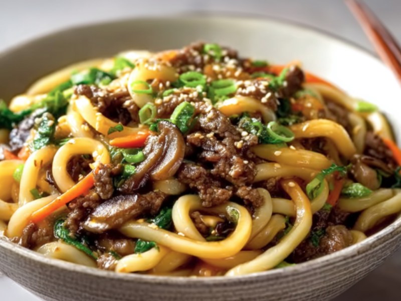 Eine Schüssel mit Bulgogi-Udon-Nudeln. Auf dem Rand liegen Essstäbchen.