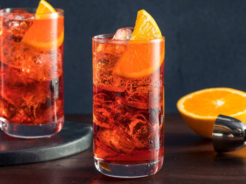 Mehrere Gläser Campari Soda mit Orangenscheiben.