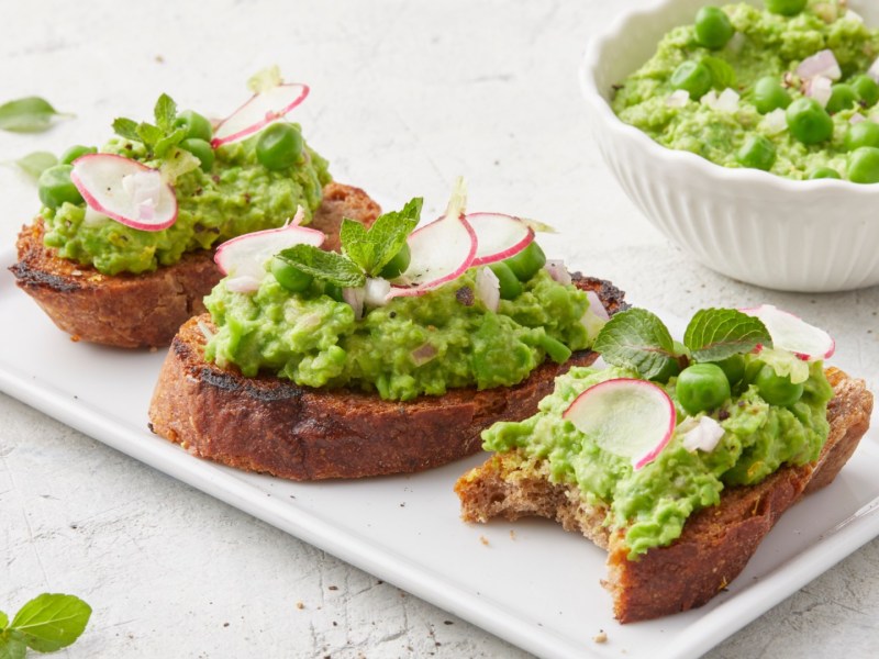 Drei Scheiben Erbsen-Bruschetta auf einem Teller.