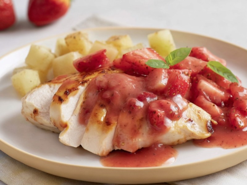 Hähnchen mit Erdbeersoße und Kartoffeln auf einem Teller.
