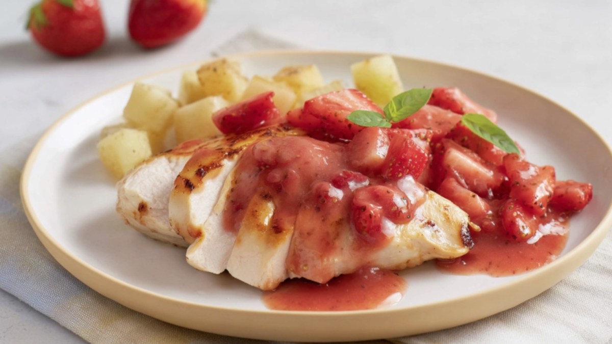 Hähnchen mit Erdbeersoße und Kartoffeln auf einem Teller.