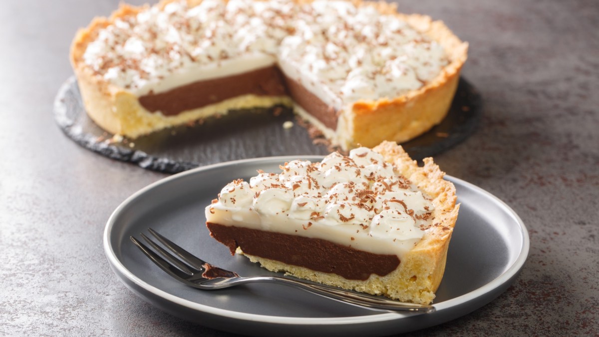 Ein Stück Haupia Pie auf einem Teller. Im Hintergrund steht der restliche Kuchen.