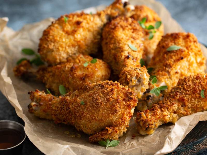 Einige Hähnchenkeulen, paniert mit Panko-Paniermehl, auf Backpapier.