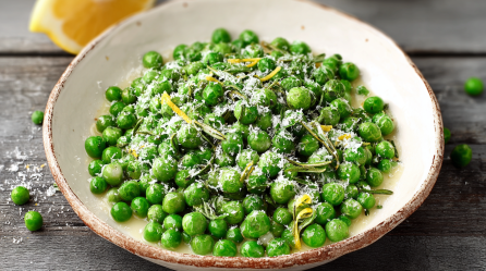 Parmesan-Erbsen mit Zitrone und Rosmarin auf einem weißen Teller.