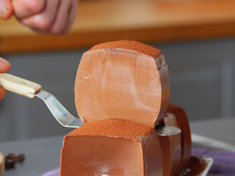 Ein Koch entnimmt ein Stück Schokopudding aus dem Milchkarton.