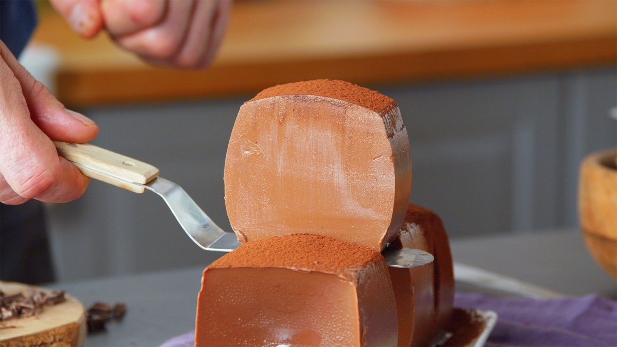 Ein Koch entnimmt ein Stück Schokopudding aus dem Milchkarton.