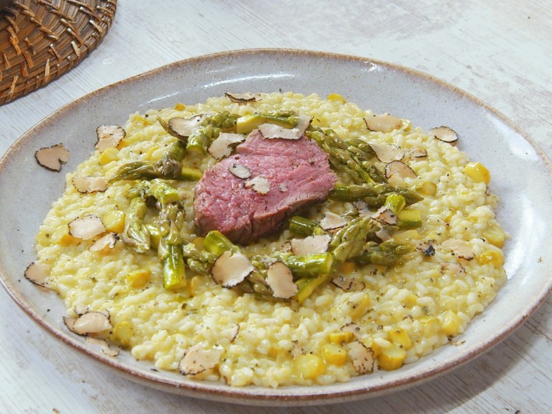 Spargelrisotto mit Rinderfilet auf einem Teller.