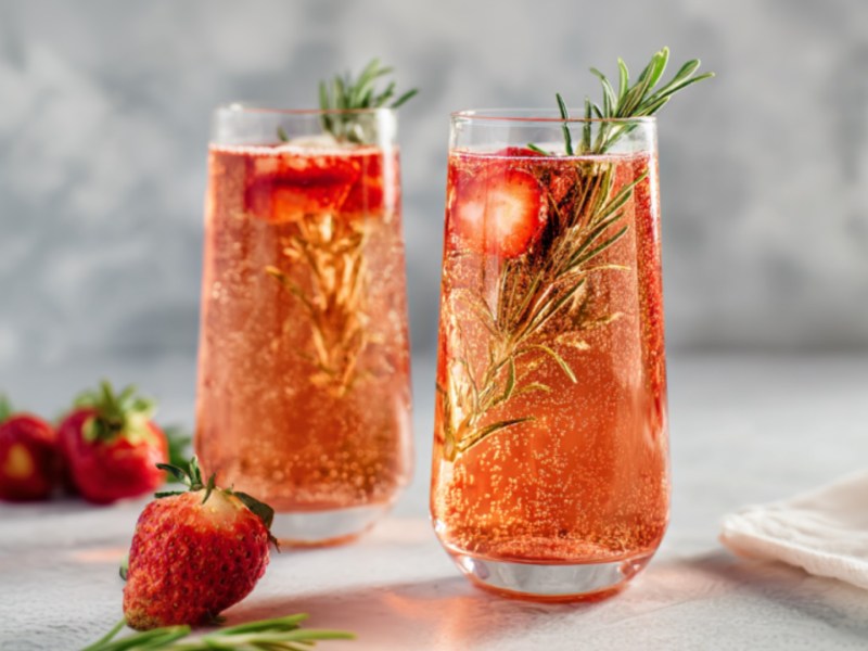 Zwei Gläser würziger Erdbeer-Sekt mit Rosmarin.