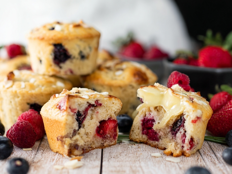 Mehrere Beeren-Brie-Muffins, im Vordergrund liegt ein durchgebrochener.