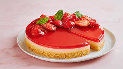 Erdbeer-Grieß-Tarte mit Erdbeeren als Dekoration. Ein Stück ist angeschnitten.