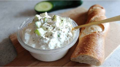 Schale mit Feta-Gurken-Aufstrich und einem Baguette daneben