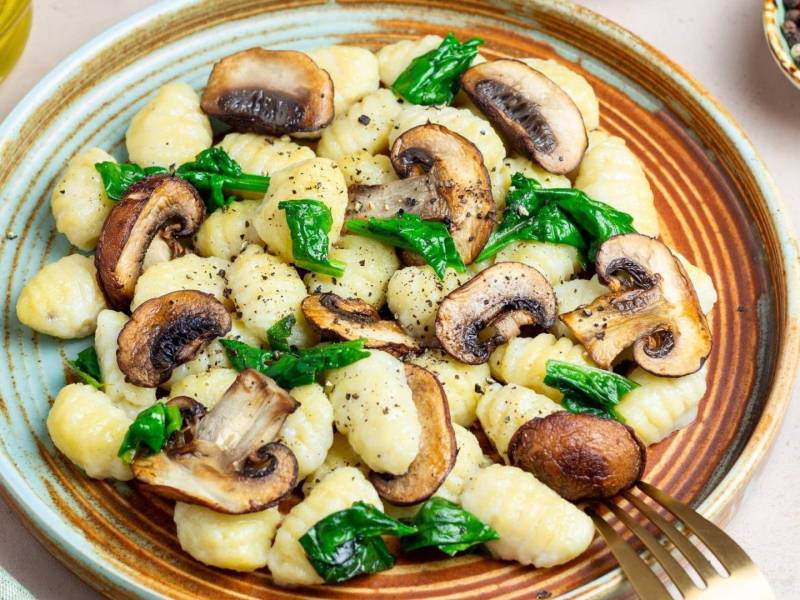 One-Pot-Gnocchi mit Pilzen und Spinat, hübsch angerichtet auf einem Teller.