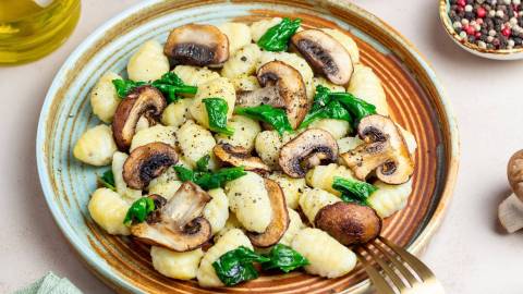 One-Pot-Gnocchi mit Pilzen und Spinat, hübsch angerichtet auf einem Teller.