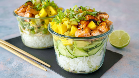 Zwei Schüsseln mit Sushi-Salat, serviert auf einem Brett. Daneben liegen Stäbchen und im Hintergrund eine aufgeschnittene Limette.