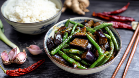 Eine Schale Auberginen-Bohnen-Stir-Fry, serviert mit einer Schale Reis.