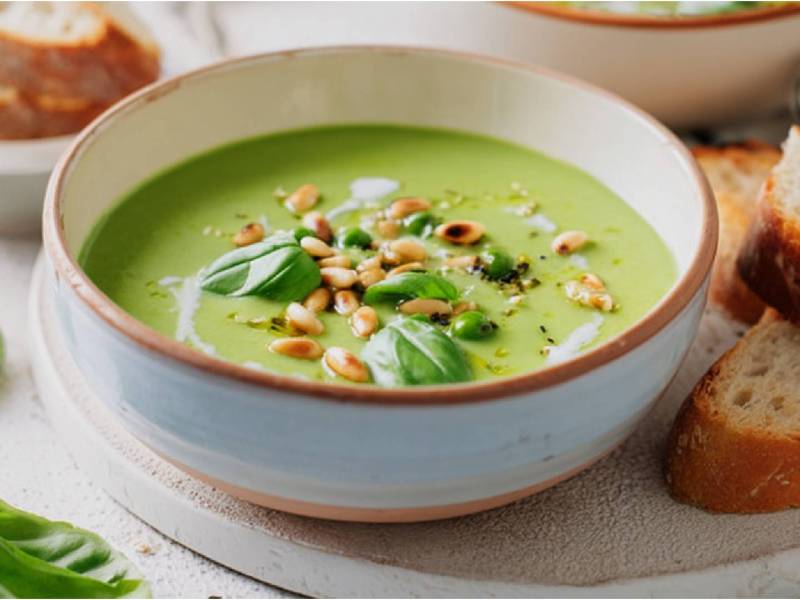 Schale mit Basilikumcremesuppe, Brotscheiben daneben