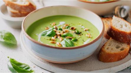 Schale mit Basilikumcremesuppe, Brotscheiben daneben