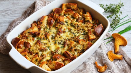 Eine Auflaufform mit Brezelauflauf mit Pfifferlingen, daneben Pfifferlinge und Thymian.