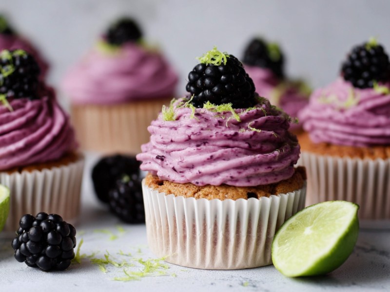 Mehrere Brombeer-Limetten-Cupcakes.