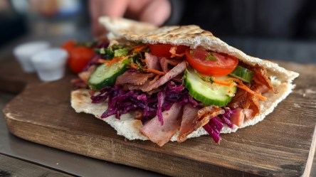 Ein DDR-Döner mit Jagdwurst und Gemüse auf einem Holzbrett.