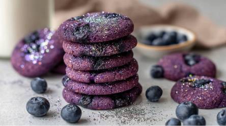 Gestapelte Heidelbeer-Cookies mit Glitzer bestäubt und frischen Heidelbeeren daneben