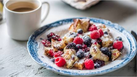 Teller mit Haferflocken-Kaiserschmarrn und einer Tasse Kaffee im Hintergrund