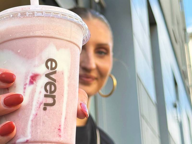 Redakteurin Nina hält einen Erdbeer-Smoothie, der Hailey Bieber's Strawberry Glaze Skin Smoothie ähnelt in die Kamera.
