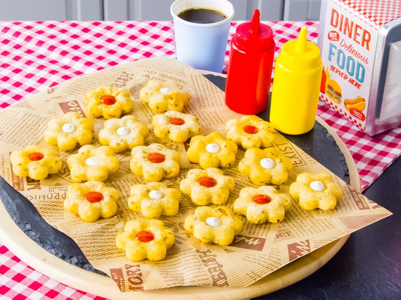 Knusprige Kartoffelblumen mit Ketchup und Mayo auf einem Teller.