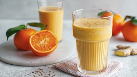 Zwei Gläser Mandarinen-Lassi. Daneben liegen frische früchte.