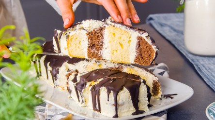 Ein Stück Metrowiec wird in die Kamera gehalten. Dahinter ist der restliche Kuchen zu sehen.