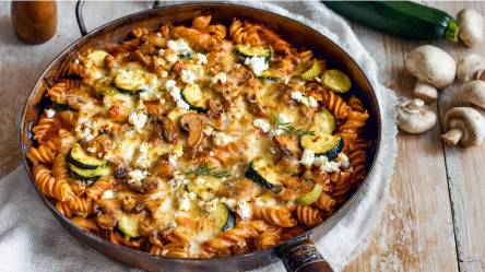 Nudelpfanne mit Champignons und Zucchini auf einem Tisch, Champignons daneben