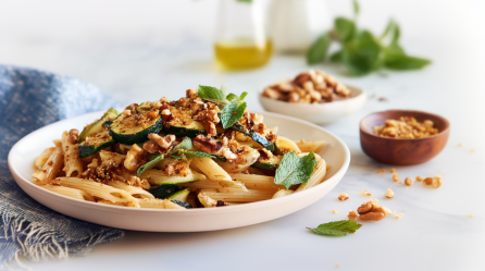 Ein Teller mit Penne mit Zucchini, Walnüssen und Minze