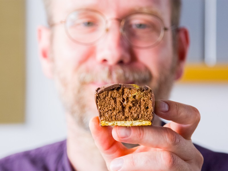 Koch Oli präsentiert einen aufgeschnittenen Schokomoussewürfel.