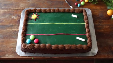 Ein Schultafel-Kuchen, der auf einer silbernen Servierplatte liegt. Der Kuchen ist mit Lebensmittel und Fondant verziert.