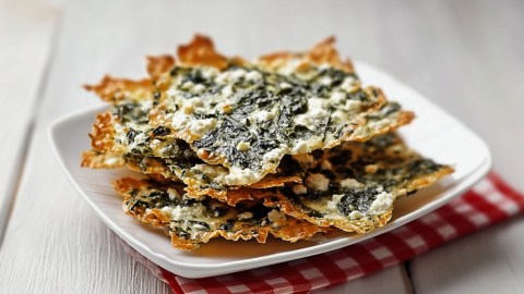Spinat-Feta-Chips übereinandergestapelt auf einem Teller.