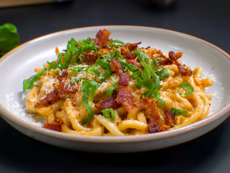 Ein Teller mit Thai-Carbonara. Basilikum und Chilischote liegen als Dekoration außen herum.